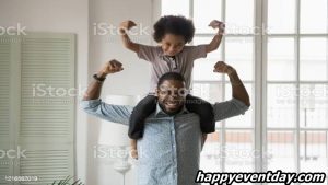 African ethnicity little son sitting on fathers shoulders showing biceps stock photo